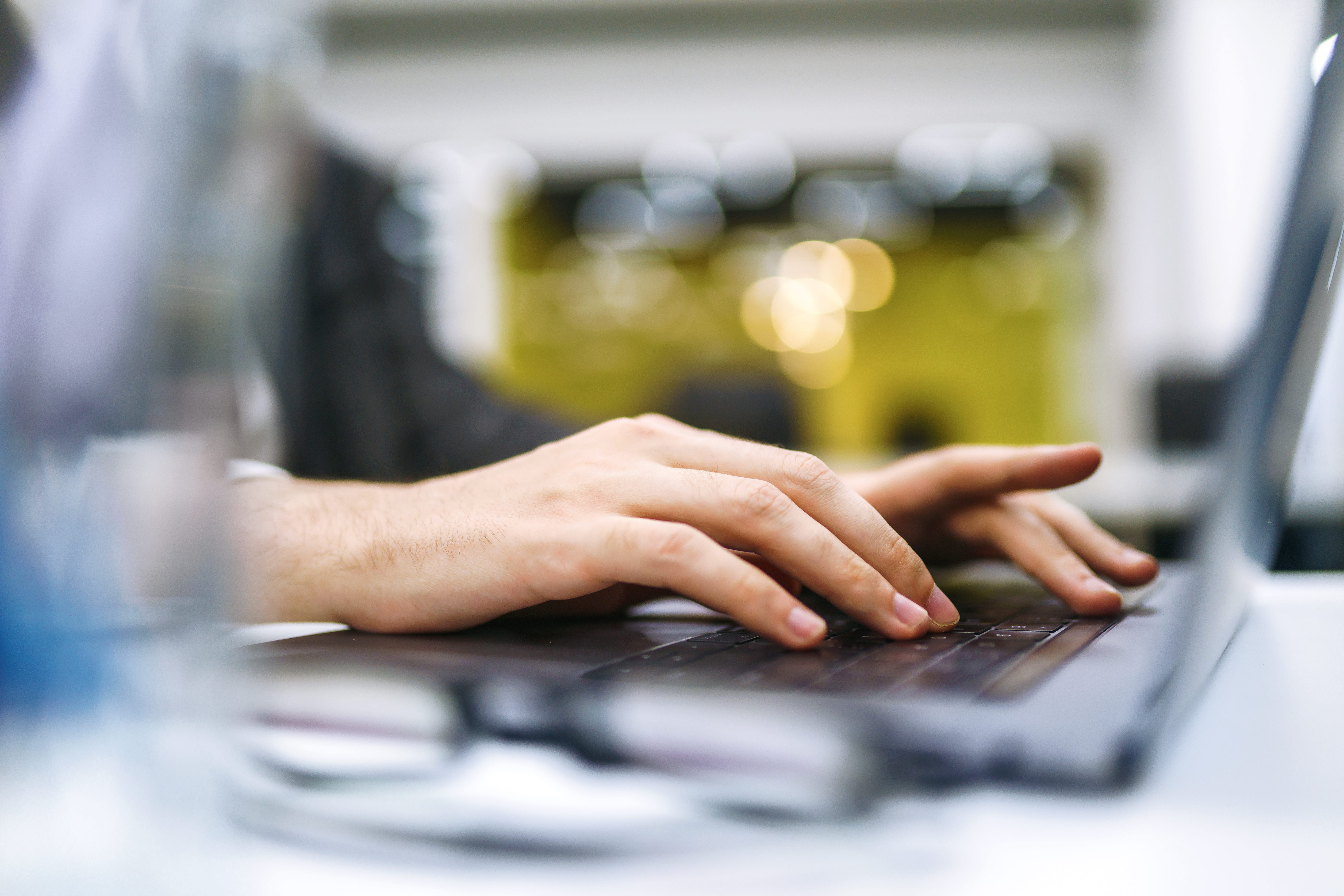Close up of man hand working on laptop computer and writing on notebook on table at home office.