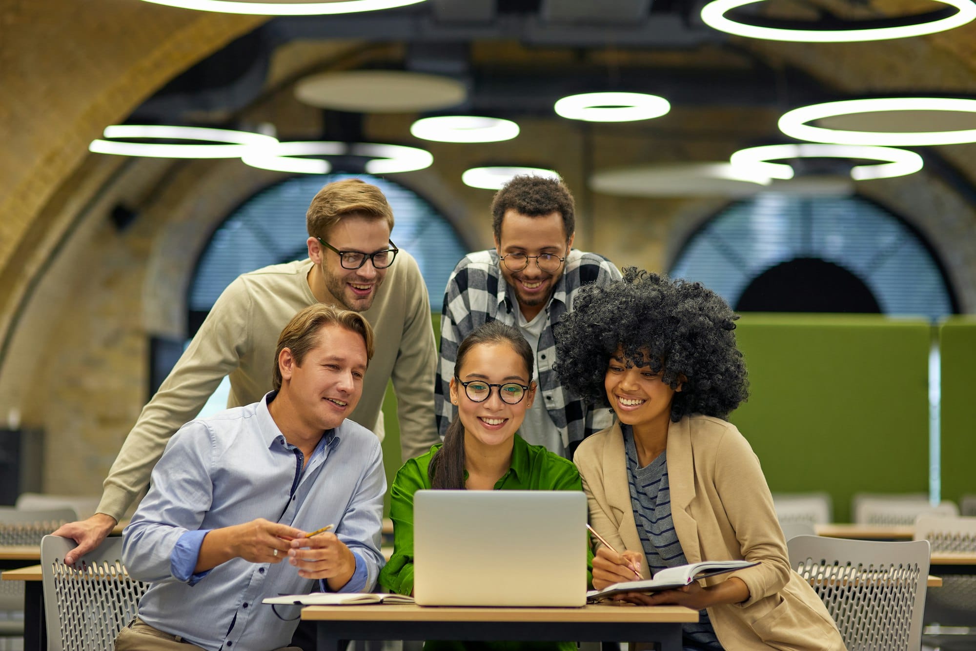 Group of young multiracial business people sitting at desk in the modern coworking space, looking at