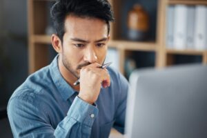 Serious, business man and thinking on computer in office, internet research and website. Focused ma